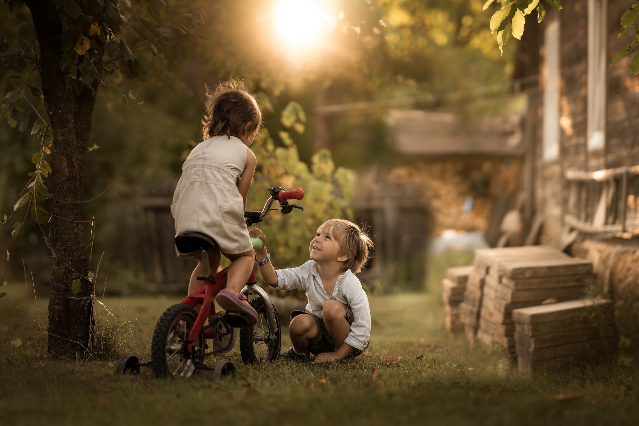 С появлением детей жизнь. Детство. Беззаботное детство. Дети на велосипедах в деревне. Мальчик и девочка на велосипеде.