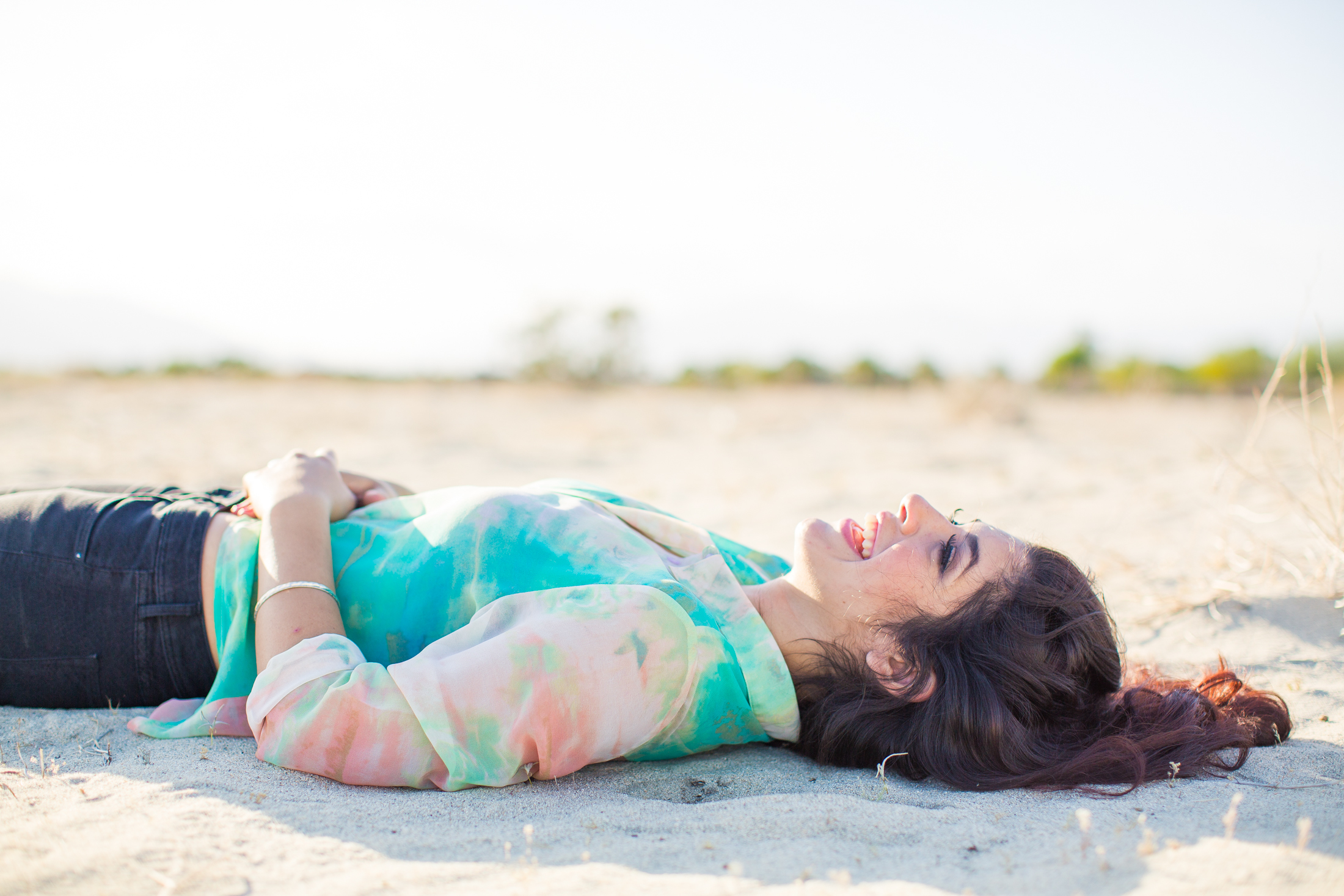 Брюнетки лежа. Девушка в платье лежит на песке. Девушка по песку. Брюнетка лежит связанная на песке. Брюнетка лежит в одежде на песке.