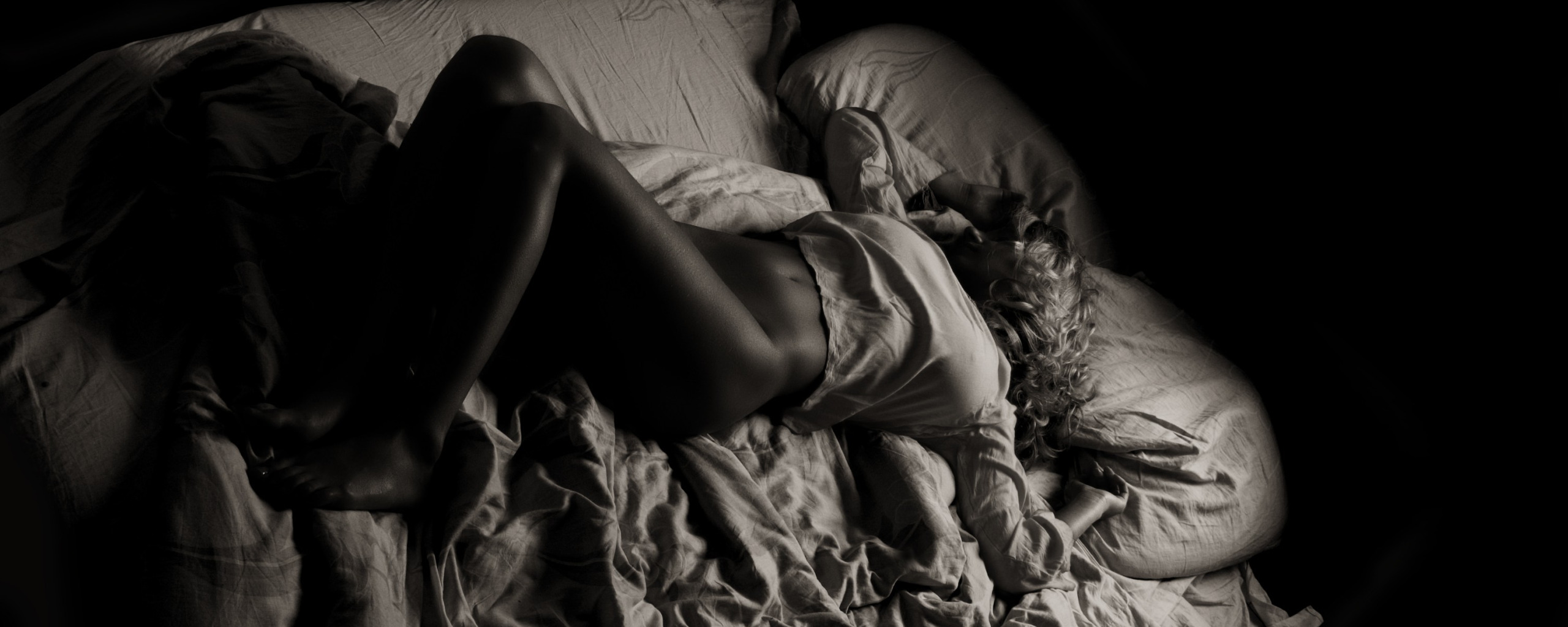 Девушка спит в темноте на кровати