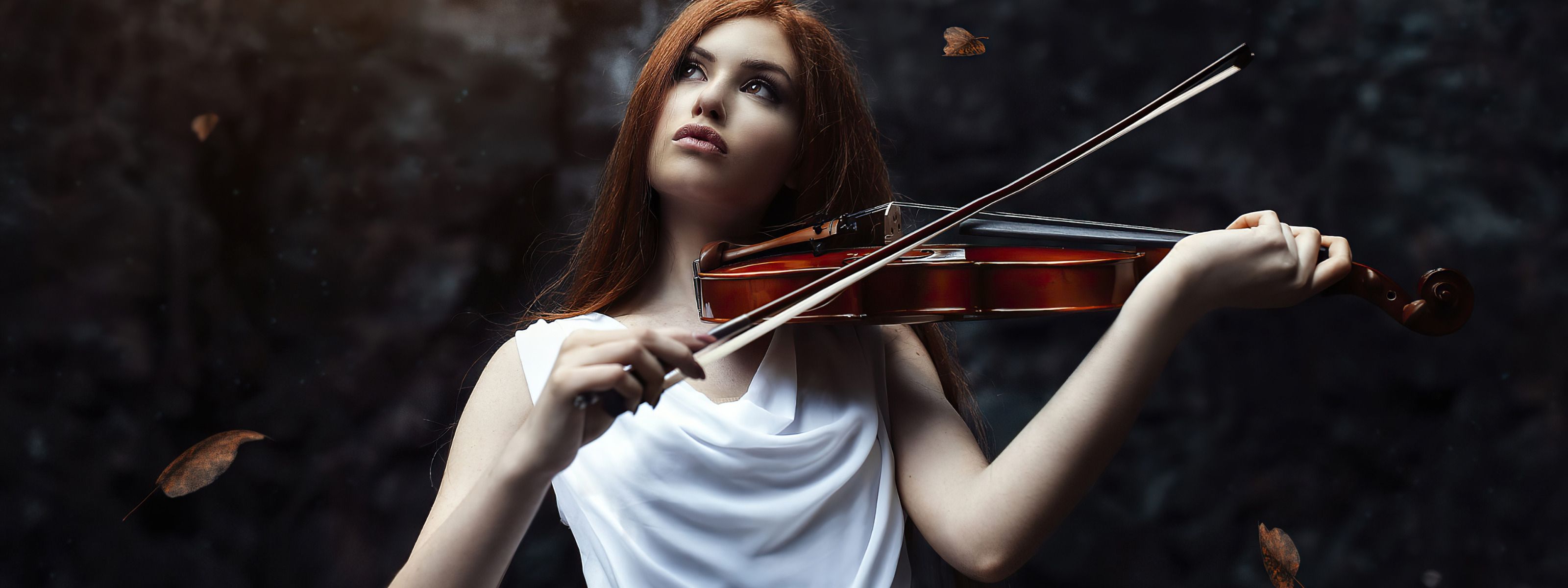 Скрипка играет слушать музыку. Талантливая девушка выступает фон. Девушка рыжая играет на скрипке черный фон.
