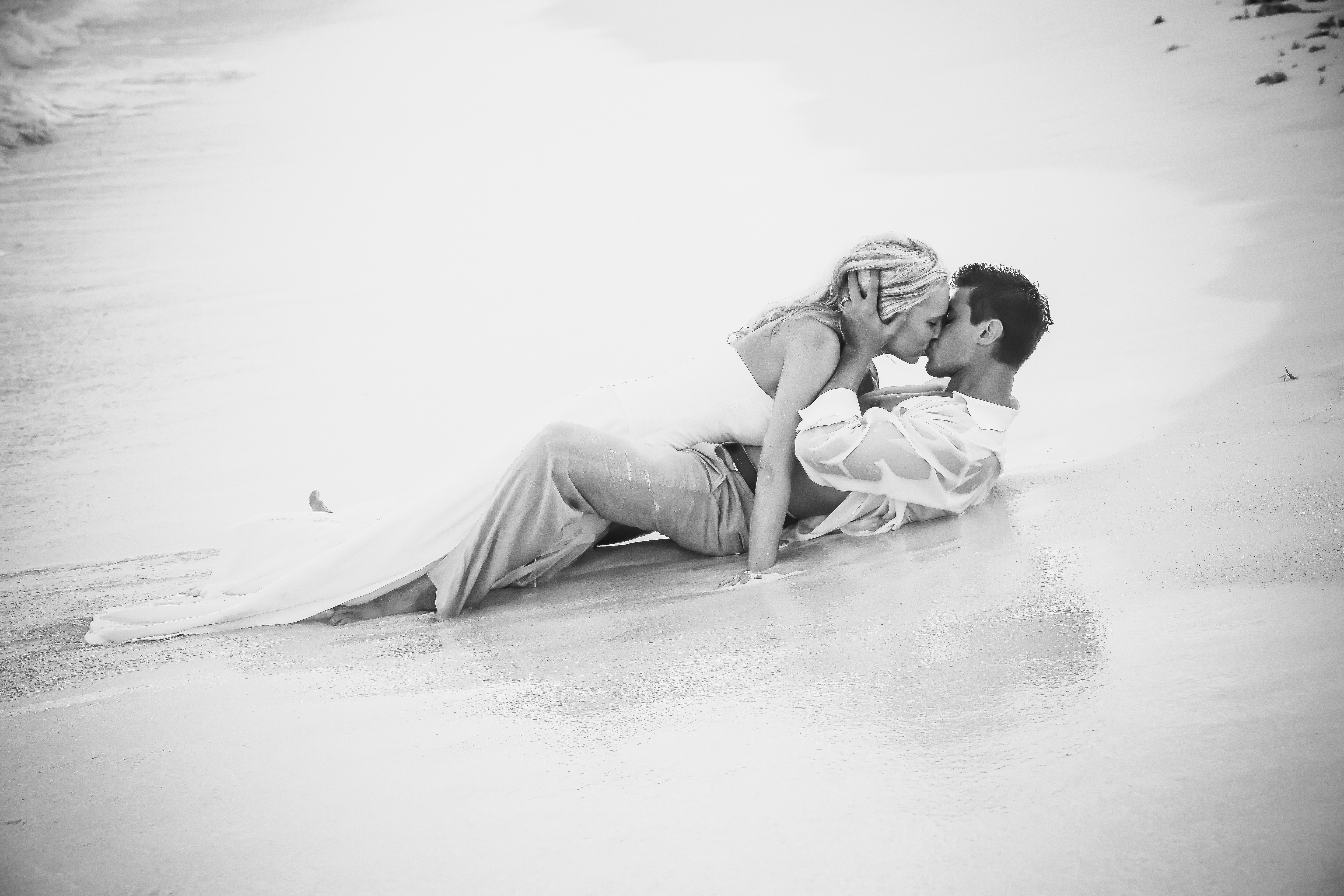 Муж целует ноги жене. Мужчина и женщина на песке. Страстный поцелуй. Нежность. Мужчина и женщина на пляже.