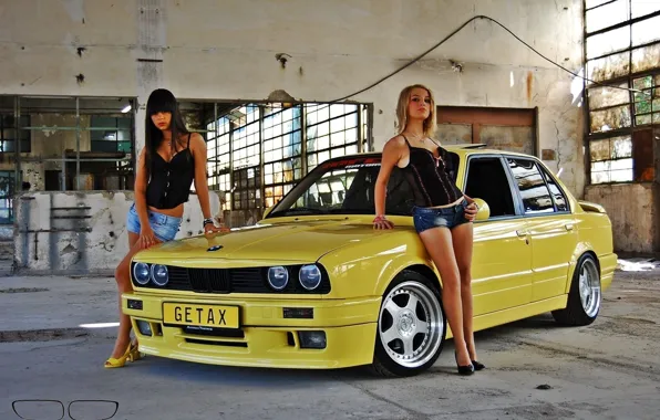 Картинка Девушки, Две красивые девушки, смотрят в камеру, стоят возле старого желтого авто BMW, Блондинка и …