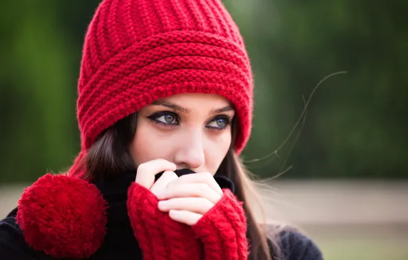 Девушка, фон, красная шапочка, руки, размытость, шатенка, помпон, пристальный взгляд