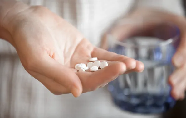 Hand, medicines, glass of water, pills