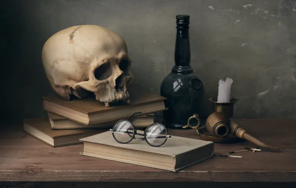 Bottle, human skull, reading glasses