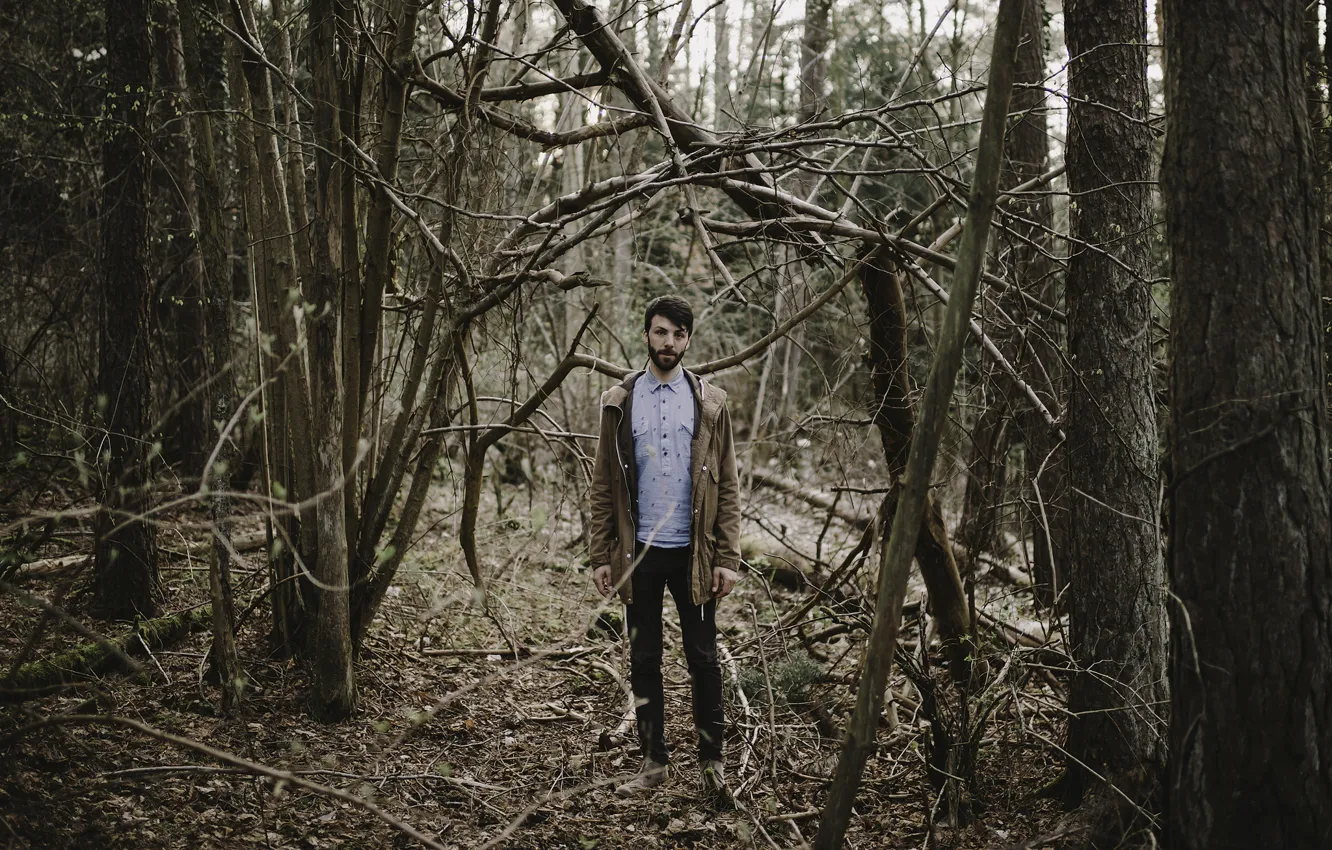 Фото обои forest, trees, man, branches, jacket, beard, direct gaze
