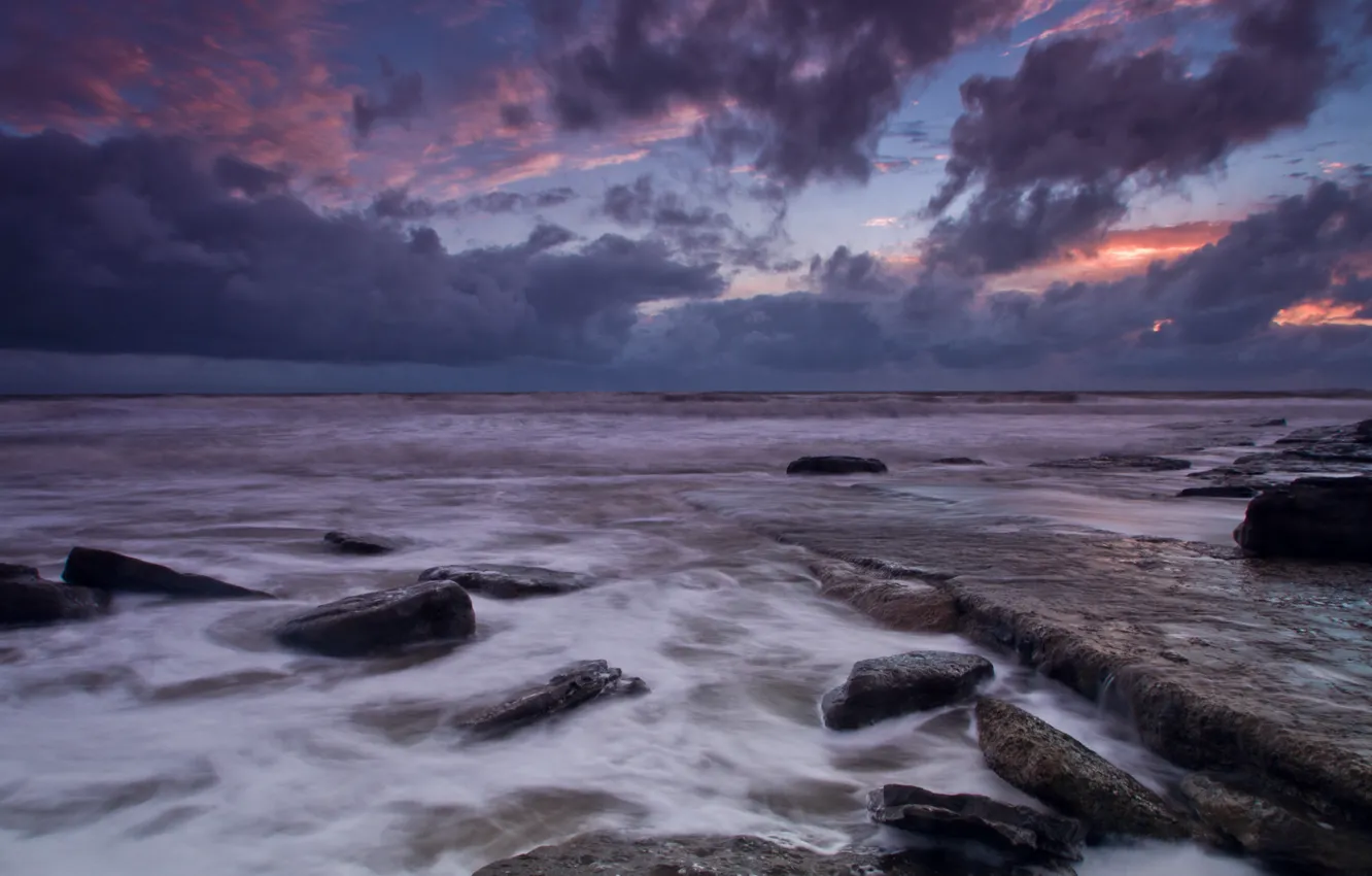 Фото обои море, небо, облака, закат, тучи, камни, берег, вечер