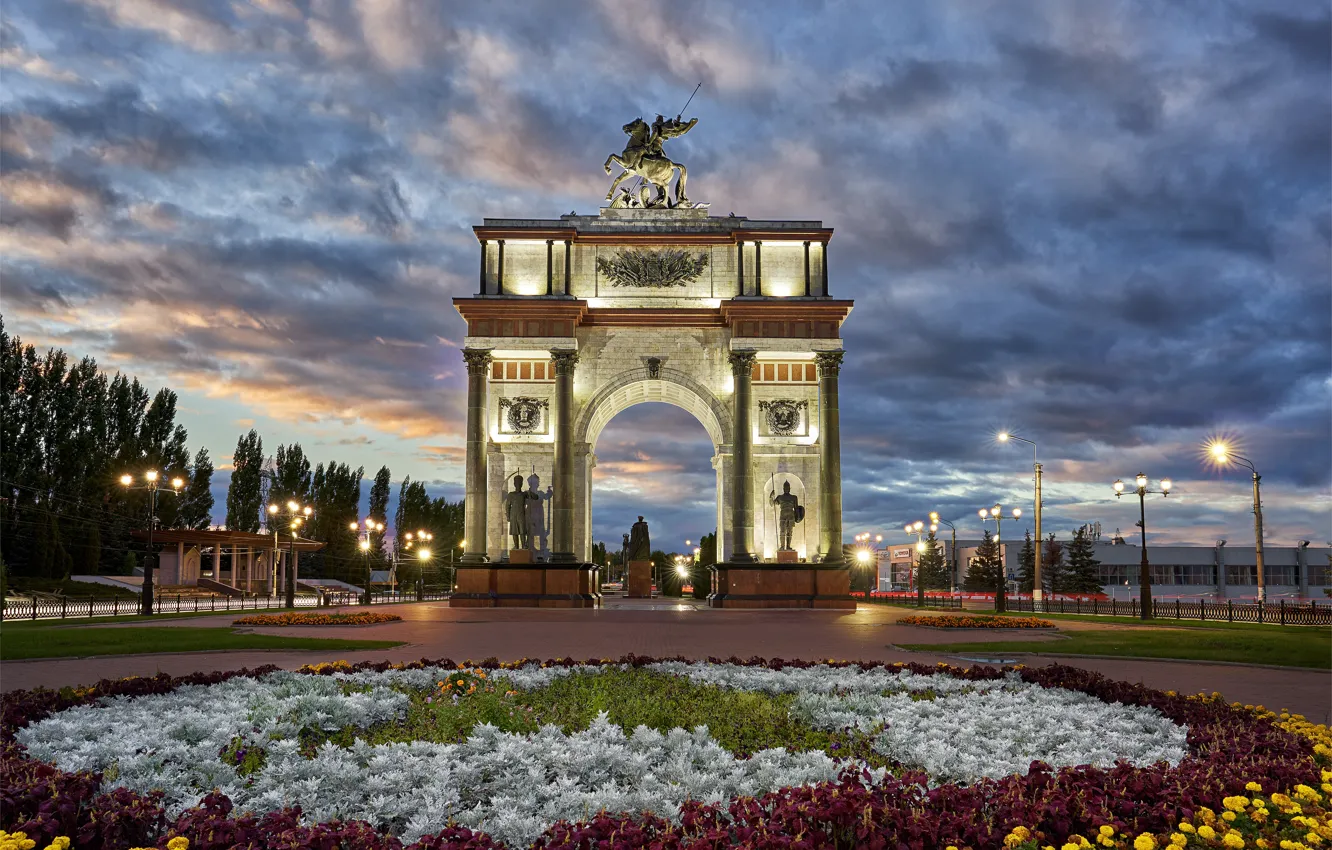 Фото обои город, вечер, освещение, фонари, клумба, триумфальная арка, Курск