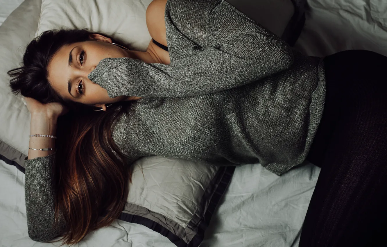 Девушка в свитере на кровати