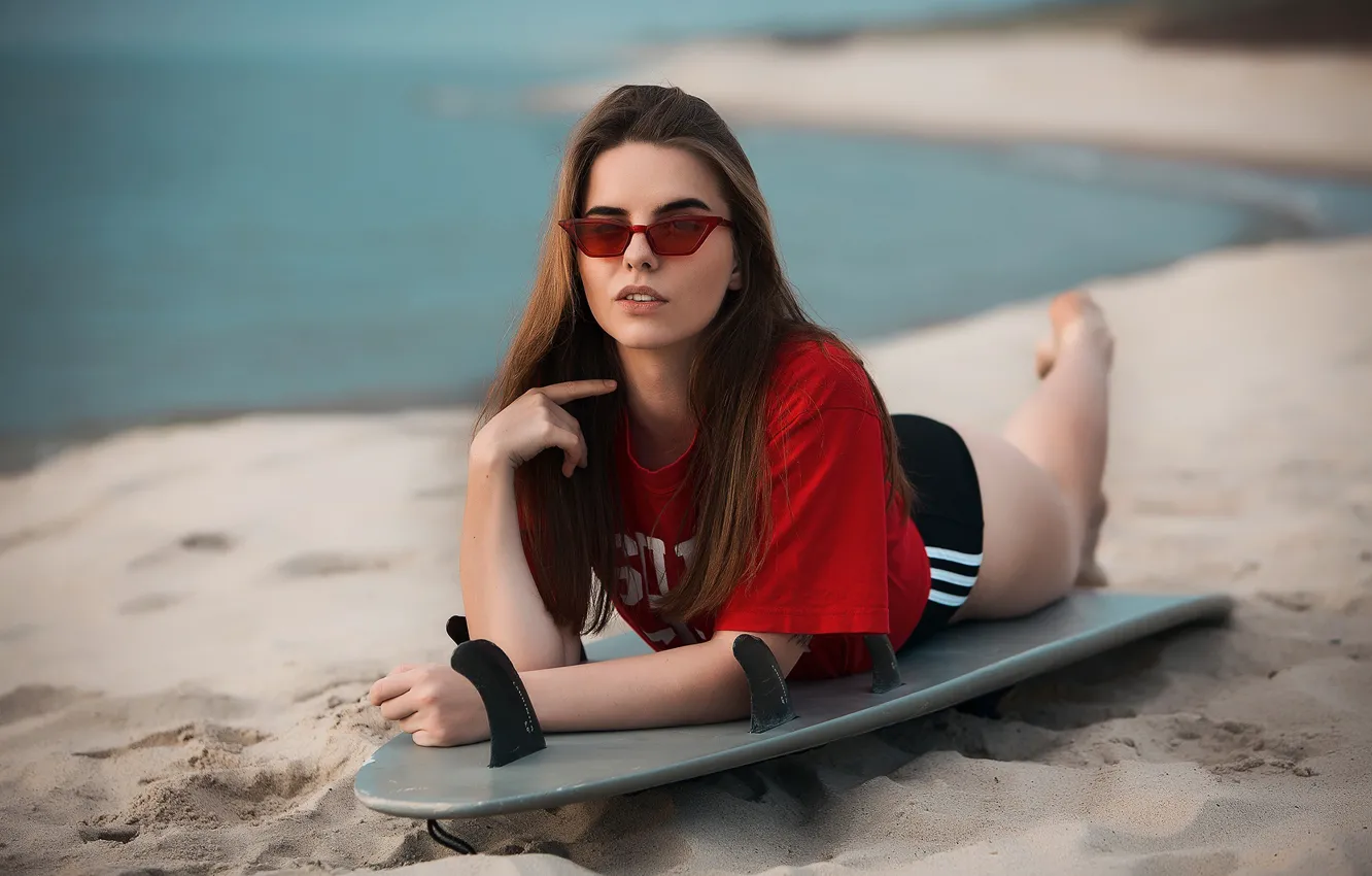 Фото обои песок, море, девушка, поза, очки, футболка, доска, сёрфинг