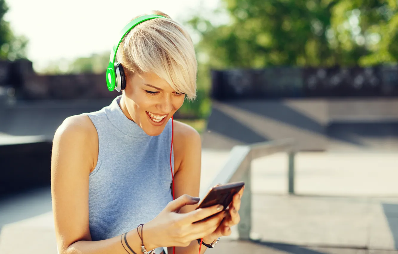 Фото обои солнце, улыбка, наушники, майка, прическа, блондинка, боке, смартфон