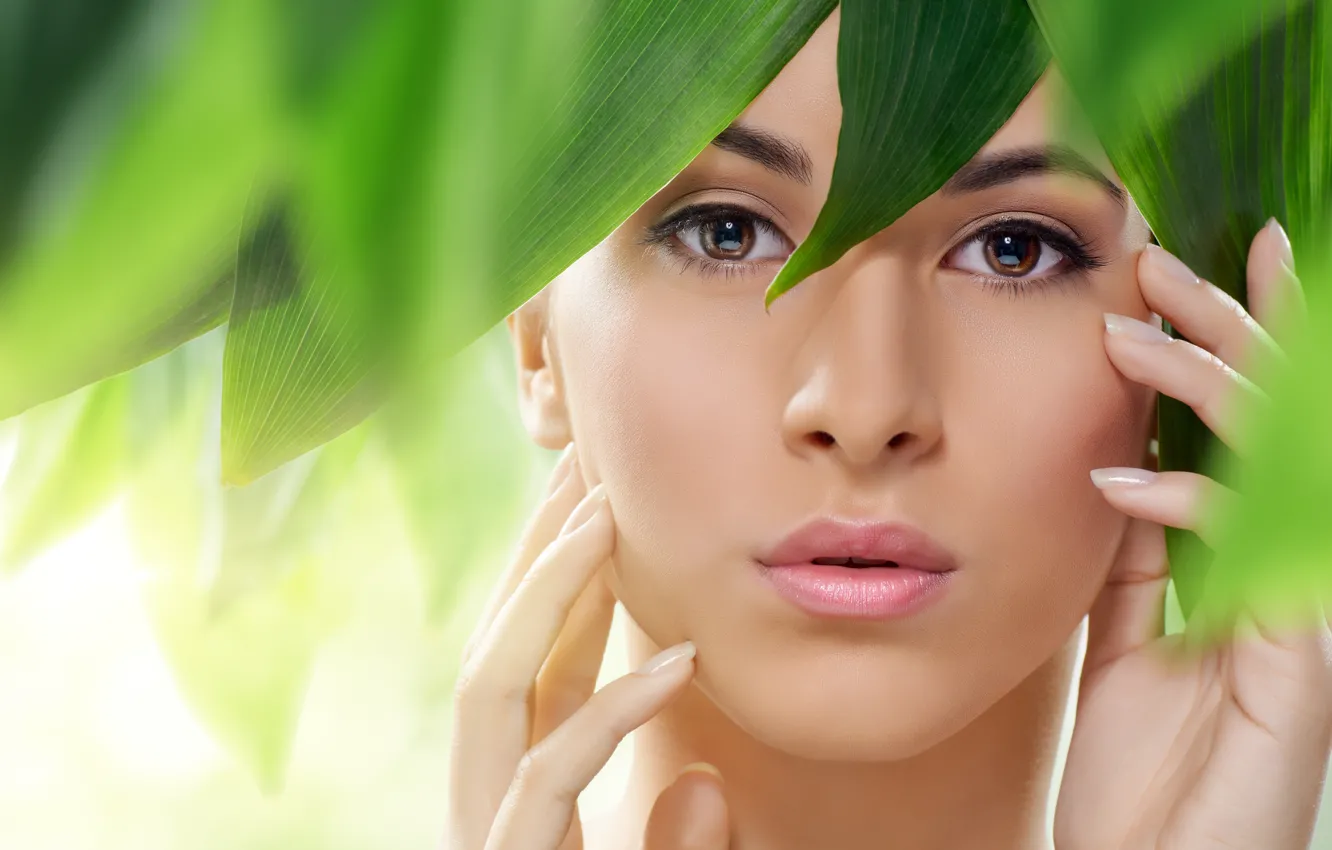 Фото обои взгляд, девушка, лицо, зеленые листья, руки, губы, карие глаза