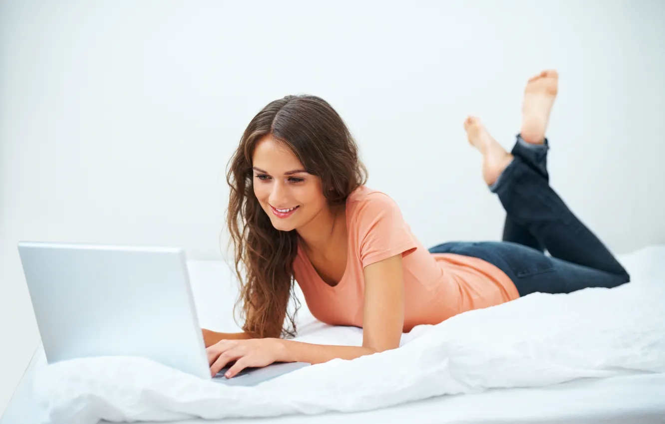 Фото обои девушка, улыбка, джинсы, постель, ноутбук, шатенка, маечка