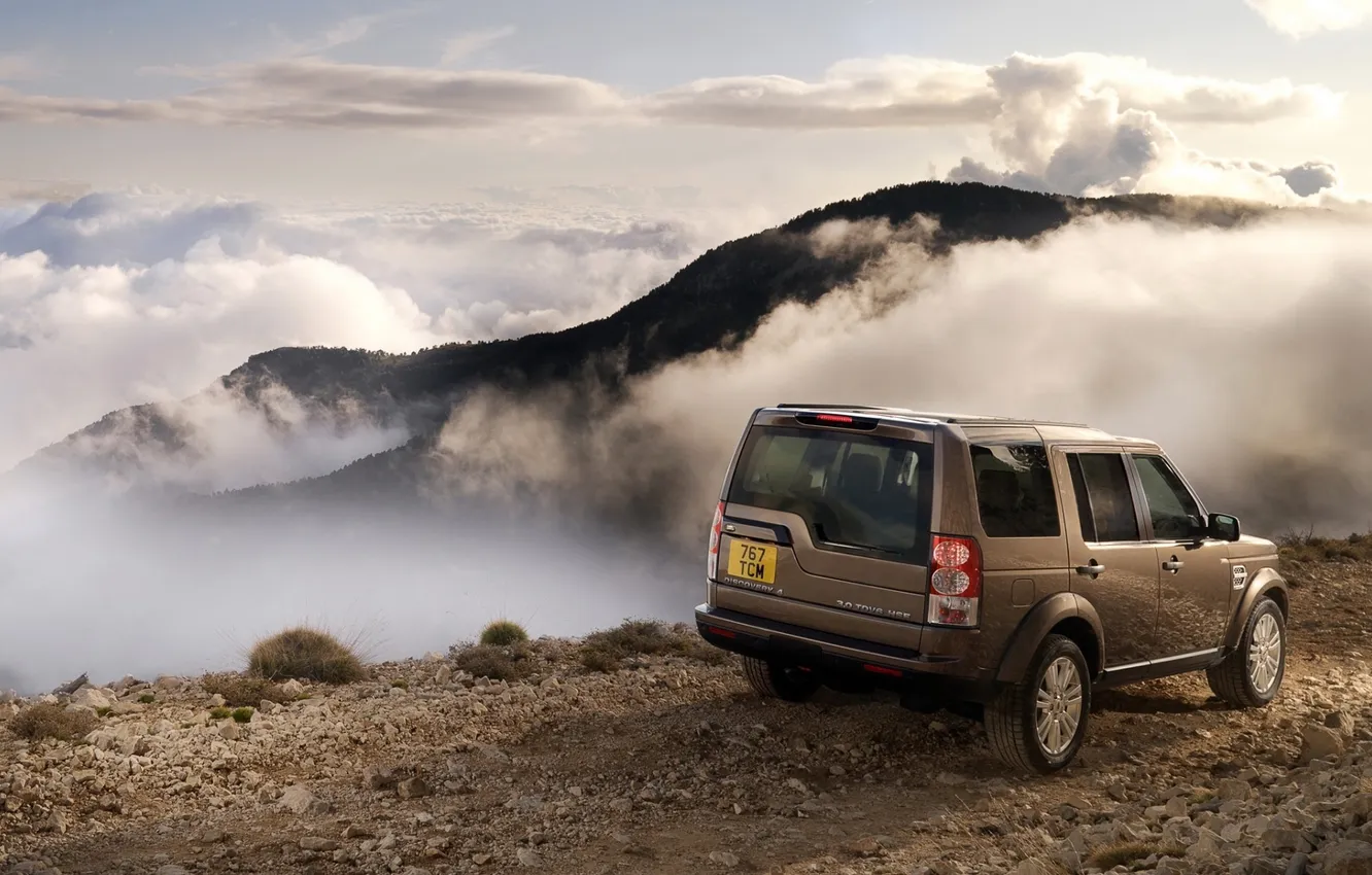 Фото обои дорога, небо, облака, горы, джип, внедорожник, Land Rover, вид сзади