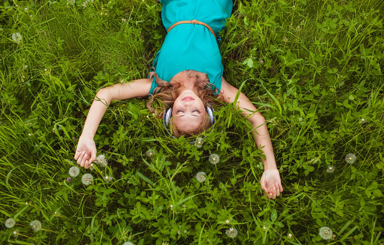 Фото обои трава, девушка, улыбка, наушники, блондинка, клевер, одуванчики, локоны