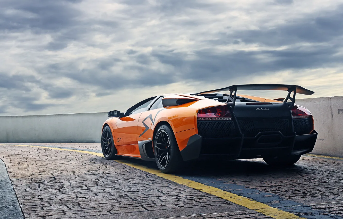 Фото обои небо, оранжевый, тучи, брусчатка, ограждение, lamborghini, murcielago, orange