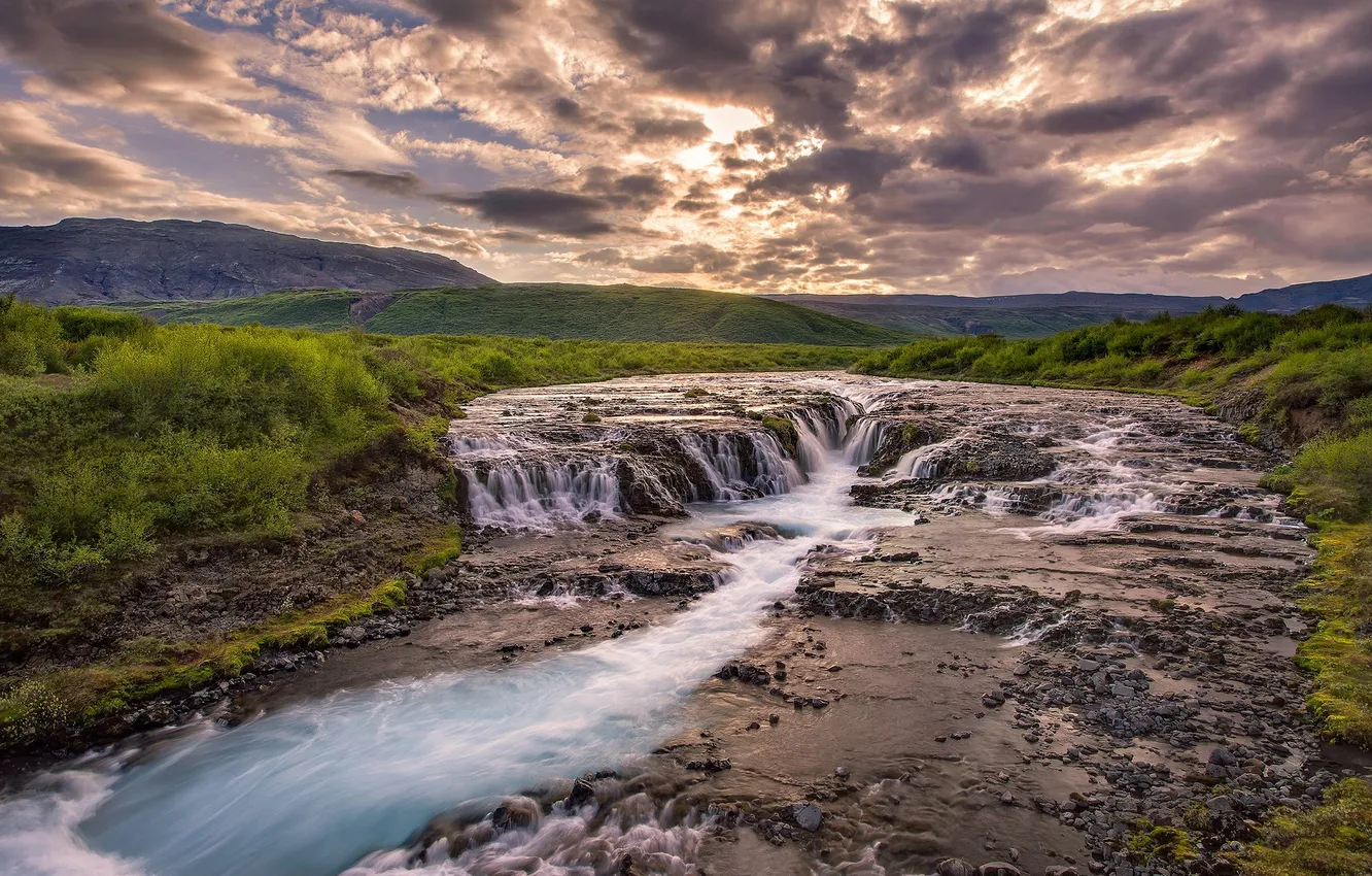 Фото обои небо, трава, облака, закат, горы, река, холмы, водопад