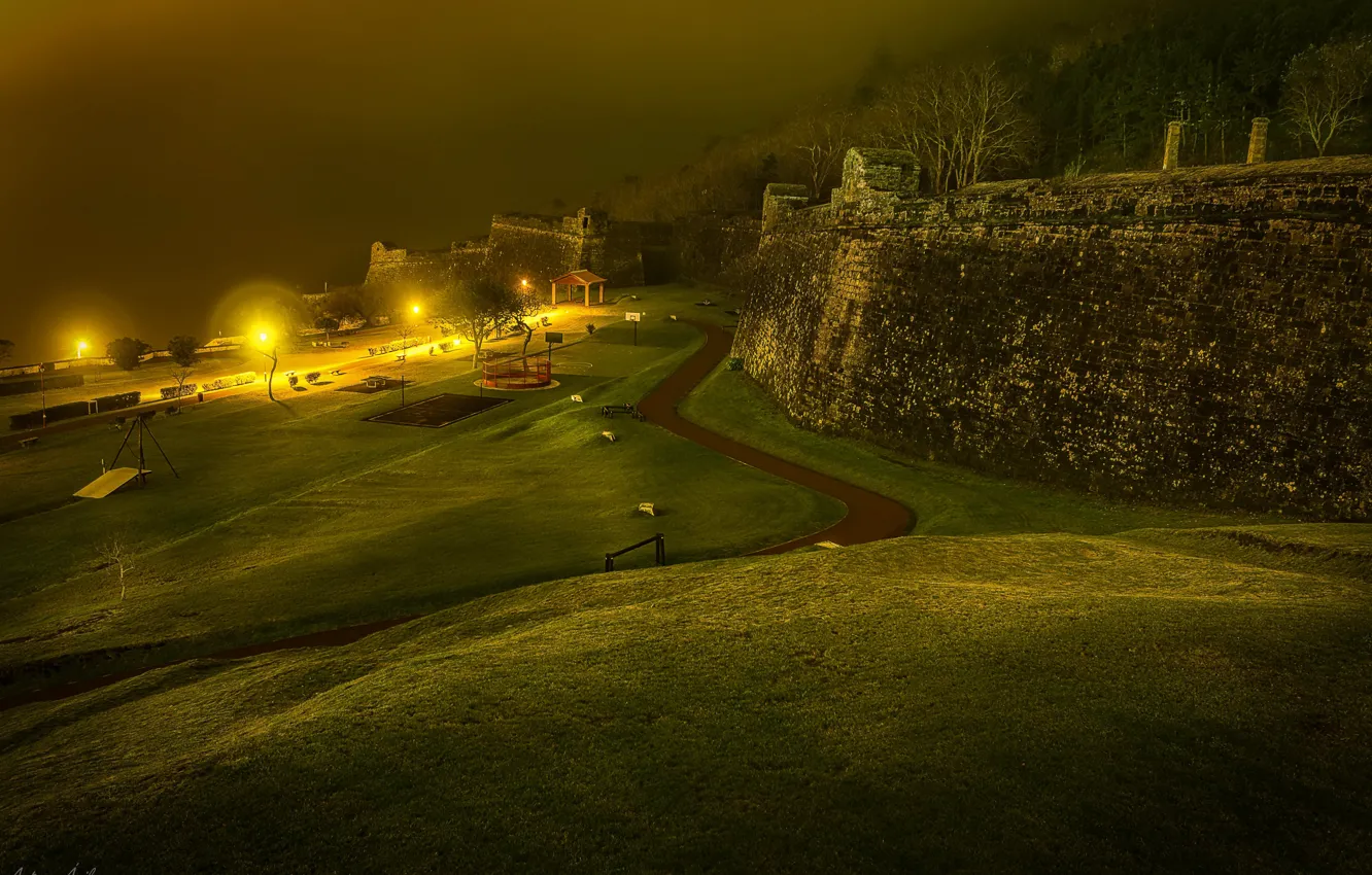 Фото обои дорога, ночь, огни, туман, газон, стены, фонари, крепость