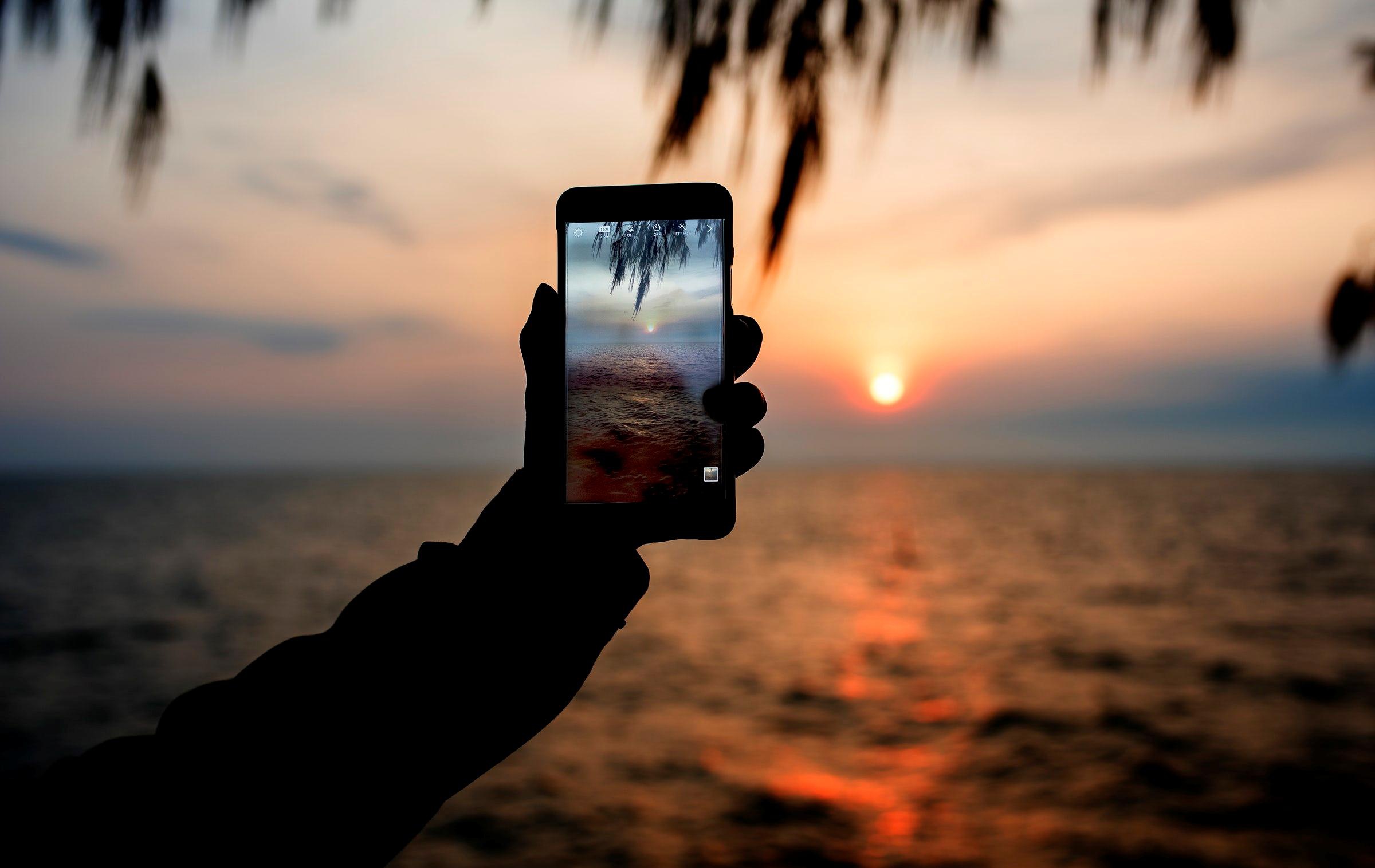 Формат фото jpg на телефоне. Фотографирует на телефон. Рука с телефоном на море. Фотографии на телефон. Фотографирует море на телефон.